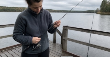 Angelanfänger mit Spinnrute am See