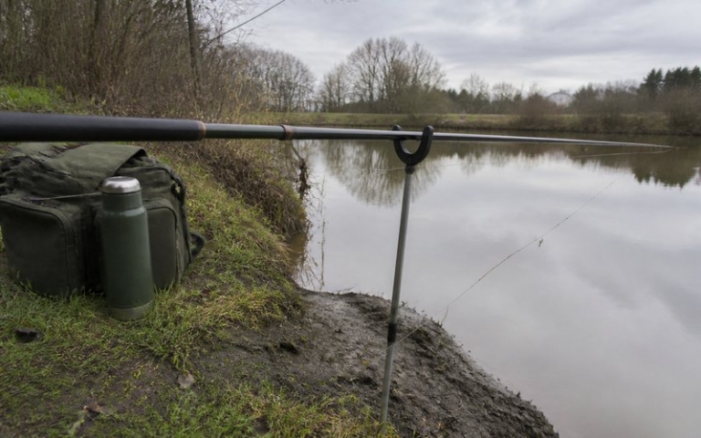 Rutenhalter mit eingelegter Angelrute am Ufer